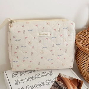 Macro detail of quilted bear and bunny print cotton cosmetic bag with brand woven label