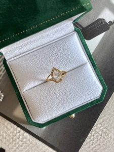 Detailed close-up of a pear-cut halo diamond ring in a green velvet jewelry gift box
