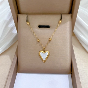 Close-up of gold heart pendant with white mother-of-pearl inlay on soft silk