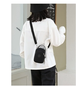 Rear view of a mini black nylon crossbody bag worn on a person for scale reference
