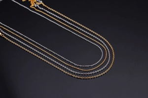 Detailed close-up of polished gold and silver link chains on a black reflective surface
