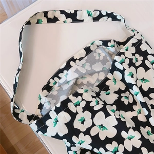 Close-up of a floral cotton tote bag with white flower prints on a black background