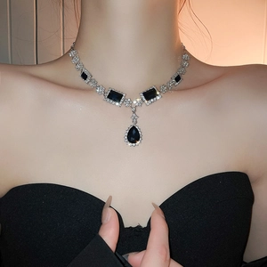 Detail of silver drop necklace featuring deep blue gemstones and rhinestones on a model