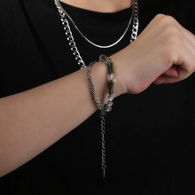 Gros plan de bracelets en chaîne argentée et perles vertes portés sur le poignet d'un modèle