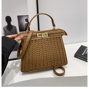 Detail of brown woven handbag with gold twist lock and adjustable shoulder strap