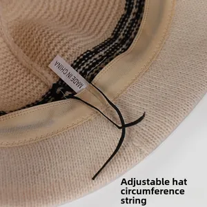Detail of knitted bucket hat inner showing adjustable drawstrings and wash label texture