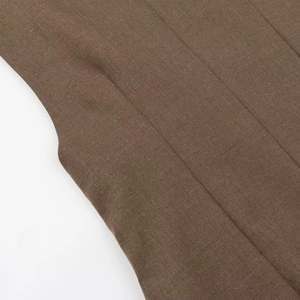 Détail de la texture du tissu tissé marron et des coutures de qualité sur la robe