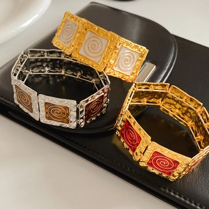 Detail of vintage enamel square link bracelets with spiral textures on black leather