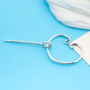 Detail of silver vintage Viking cloak pin showing metal heart-shaped buckle and shawl clip