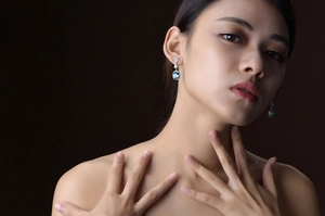 Detail view of elegant silver drop earrings with blue square gems worn by a model
