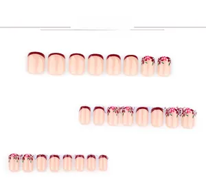 Macro detail of red French tip press on nails with delicate floral hand-painted designs