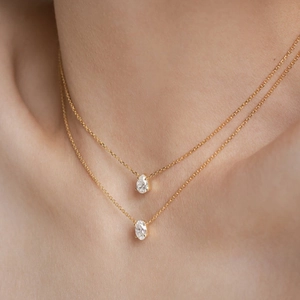 Close-up of double-layer gold necklace featuring teardrop and oval zircon pendants