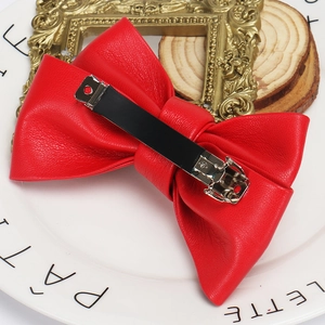 Detail shot of a premium red faux leather bow hair clip on a white decorative plate