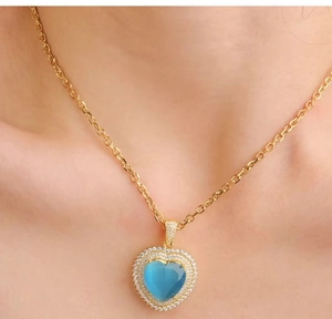 Detail of blue topaz heart pendant with double diamond halo on a gold necklace