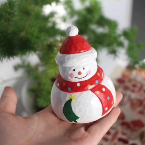Detailed view of a hand-carved wooden snowman figurine with a festive red hat and scarf