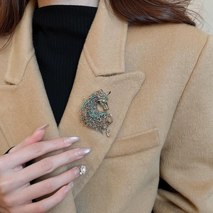 Macro detail of retro hollow horse brooch with colorful zircons on a camel coat lapel