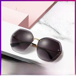 Detail of oversized rimless hexagonal sunglasses with gradient purple lenses and gold bridge
