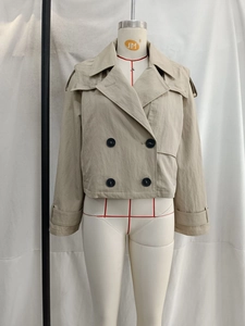 Detail of beige double-breasted short trench coat with classic lapels and black buttons