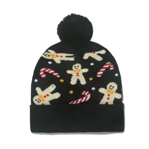 Detail of black knit Christmas hat featuring pom-pom, gingerbread man and candy cane patterns