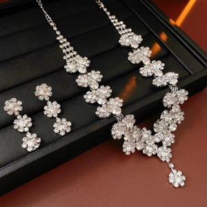 Close-up of sparkling silver sunflower jewelry set with rhinestones on a black display tray