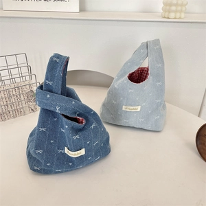 Detail view of denim knot bags with bow prints and classic red checkered inner lining