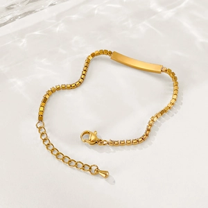 Close-up of golden stainless steel bracelet with a sleek bar, lobster clasp, and extender