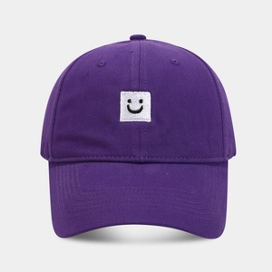 Détail d'une casquette de baseball en coton violet avec un écusson brodé de visage souriant