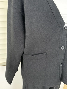 Detailed close-up of the ribbed pocket and high-density knit fabric on a black cardigan