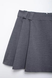 Detail shot of the dark grey pleated mini skirt showing belt loops and side hidden zipper