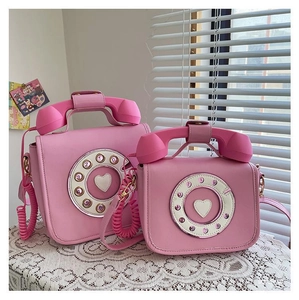 Pink vintage telephone shaped handbag in two sizes displayed on white lace cloth