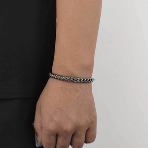 Rainbow-colored stainless steel Cuban chain bracelet shown worn on a wrist with black attire