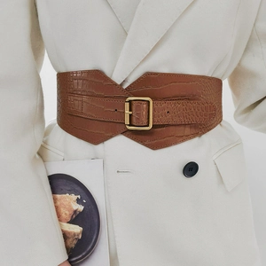 Close-up of wide crocodile texture leather belt with vintage gold buckle on white blazer