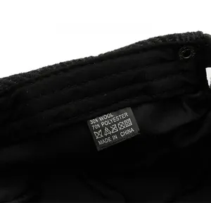 Detail of care label on black newsboy hat showing 30% wool and 70% polyester material