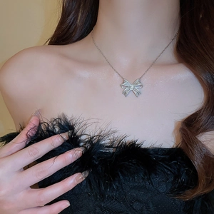 Detail of zircon bowknot necklace pendant on model wearing black feather dress