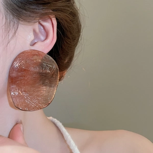 Close-up of irregular amber resin earring with ice-crack texture on a model's ear