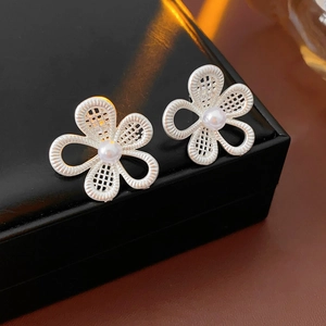 Vue rapprochée de boucles d'oreilles fleurs en argent avec perles blanches centrales