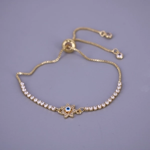 Detail of adjustable gold star bracelet featuring evil eye charm and white zircons