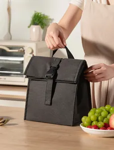 Detail view of a dark grey insulated lunch bag with buckle closure in a kitchen setting