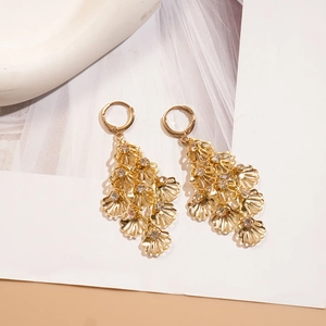 Detailed view of gold shell earrings with layered crystals on white tulle background