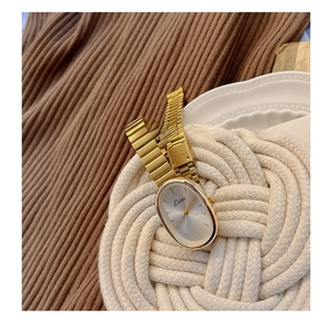 Detail of elegant gold oval ladies watch with sunray silver dial and metal chain strap