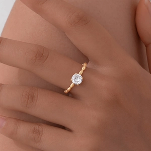 Close-up of a gold Mobius ring with a single zircon worn on a model's finger