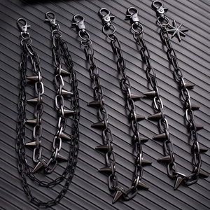 Macro detail of gunmetal punk trousers chains featuring metal spikes and star charms