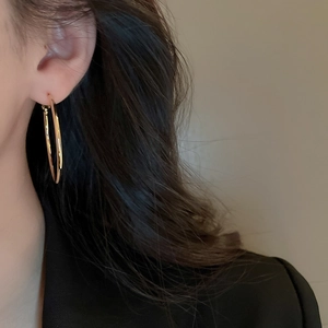 Close-up of model wearing large gold hoop earrings with minimalist geometric design