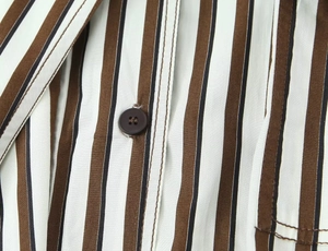 Détail de rayures verticales brunes sur coton avec boutons en résine et coutures fines