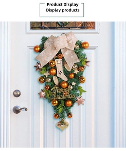 Detail of Christmas teardrop wreath with gold baubles and Merry Christmas sign on white door