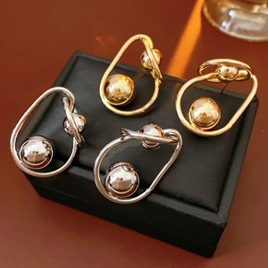 Detailed view of twisted gold and silver metallic ball drop earrings on black jewelry box