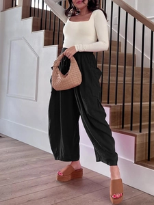 Detail view of high waist wide leg pants with elastic waist and pleated fabric texture