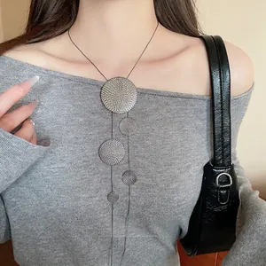 Minimalist silver geometric round pendant tassel necklace on a grey knit top