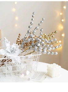 Detail of glittered gold and silver Christmas berry stems in a white wire basket