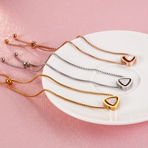 Détail de bracelets avec pendentif triangle en or et argent sur fond rose